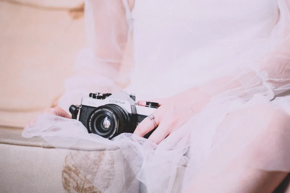 Cámara de fotos sobre un vestido blanco, trabajo de nuestro fotógrafo en Granada